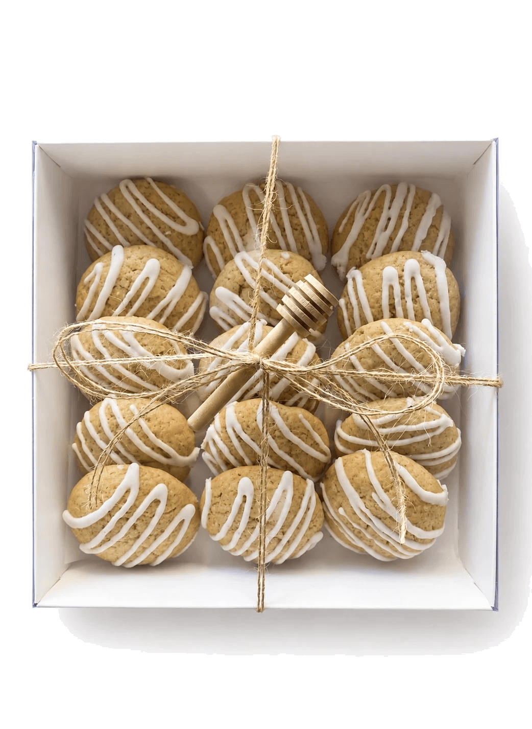 Honey glazed cookies arranged in a gift box with twine and a wooden honey dipper